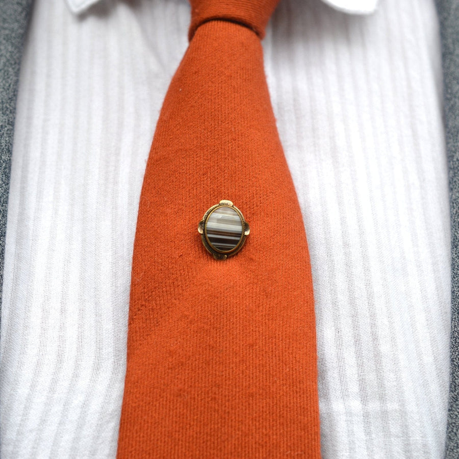 Victorian 9ct gold banded agate tie pin displayed on an orange tie, showcasing elegant Scottish jewelry craftsmanship.