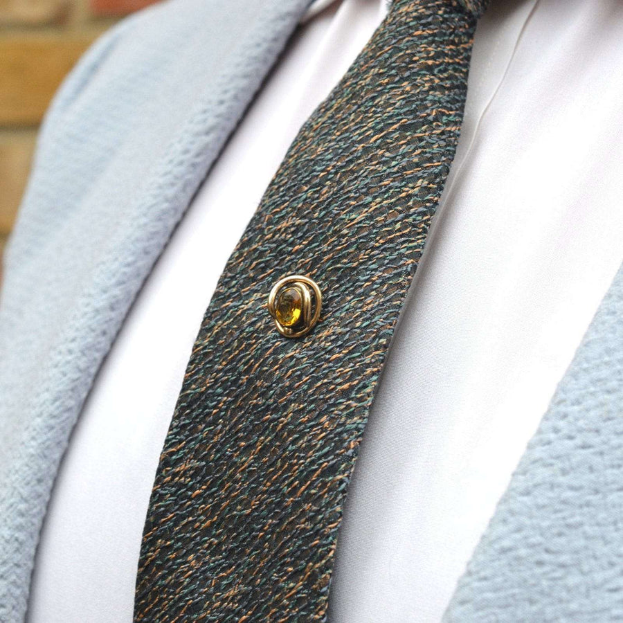 Victorian 9ct gold tie pin featuring fiery citrine paste, styled on a textured colorful silk tie.