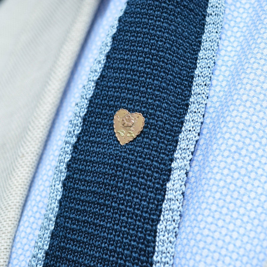Victorian 9ct gold tie pin featuring a two-tone heart design with rose motif on a knitted fabric background.