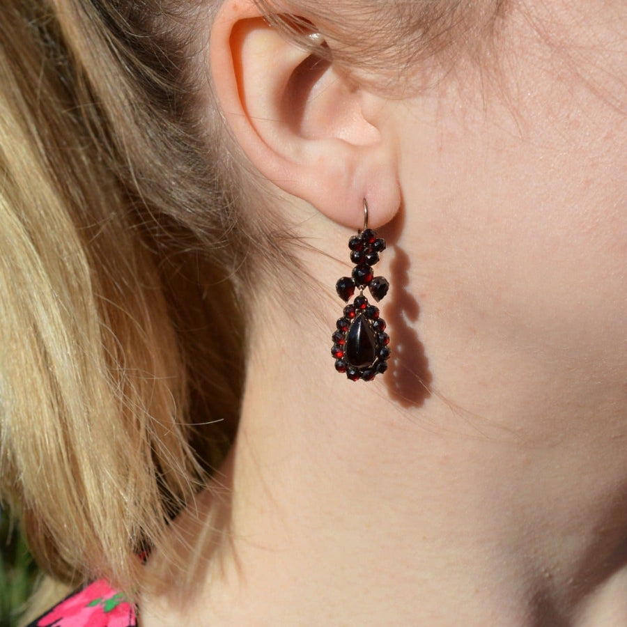 Victorian gold earrings with Bohemian garnets displayed on a model's ear, showcasing their vintage beauty.