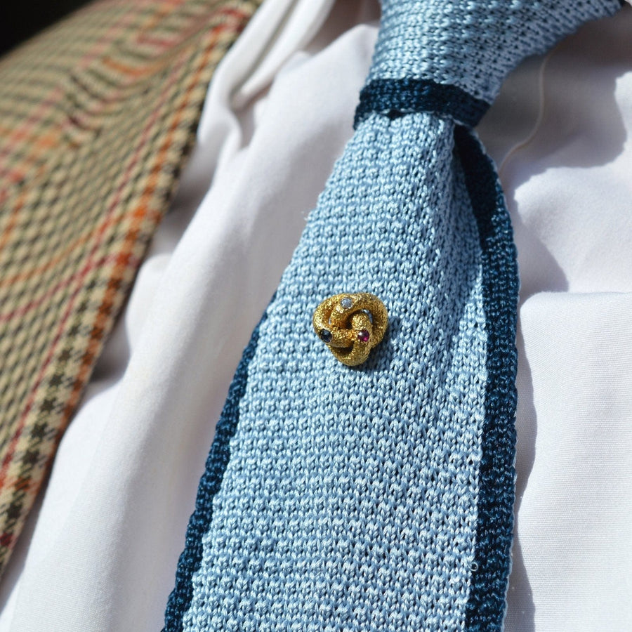 Victorian 15ct gold knot tie pin with sapphire, diamond, and ruby on blue tie, showcasing timeless elegance.