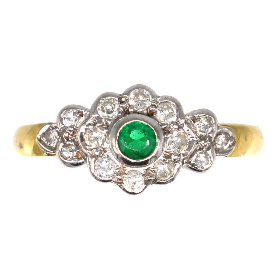 Vintage 18ct gold emerald and diamond cluster ring featuring a central green emerald and sparkling diamond shoulders.