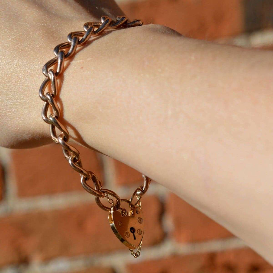 Vintage 9ct gold curb bracelet with heart lock, showcasing elegance and charm customization.