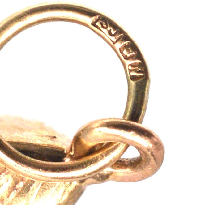 Close-up of a 9ct gold mussel shell charm showing the hallmark and attachment loop.