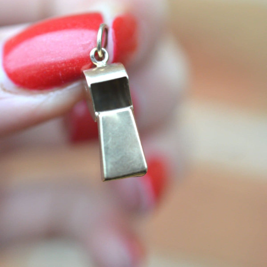 Vintage 9ct gold whistle charm pendant held between fingers with red nails, crafted in 1973, fully hallmarked.