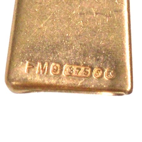 Close-up of a vintage gold hallmark on a 9ct gold whistle charm pendant, dating back to 1973.