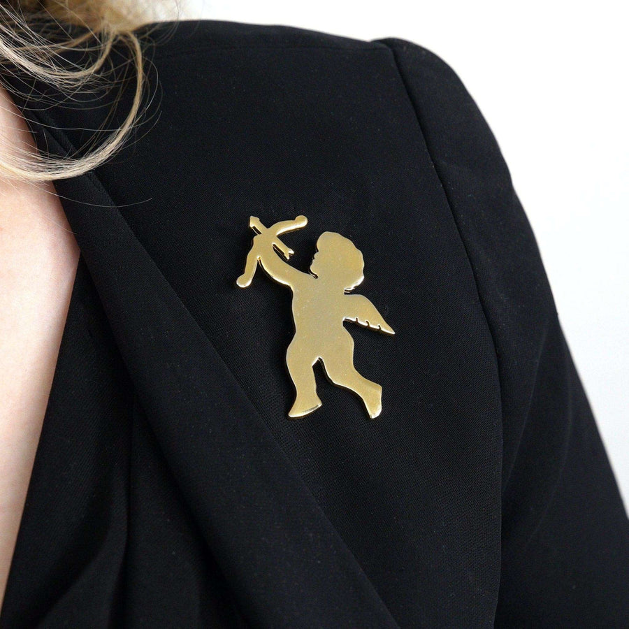 Vintage gold-tone cupid brooch with bow and arrow, worn on a black blazer.