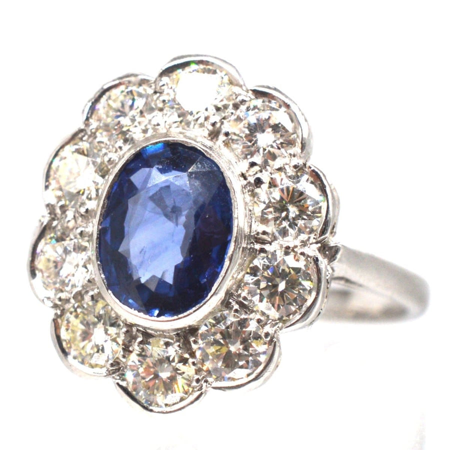 Vintage platinum sapphire and diamond cluster ring with a 1 carat sapphire and 1.2 carats of diamonds in a scalloped setting.