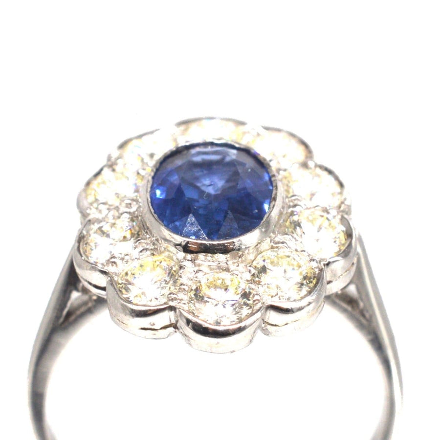 Vintage platinum sapphire and diamond cluster ring with a 1 carat sapphire and shimmering diamonds in a floral design.